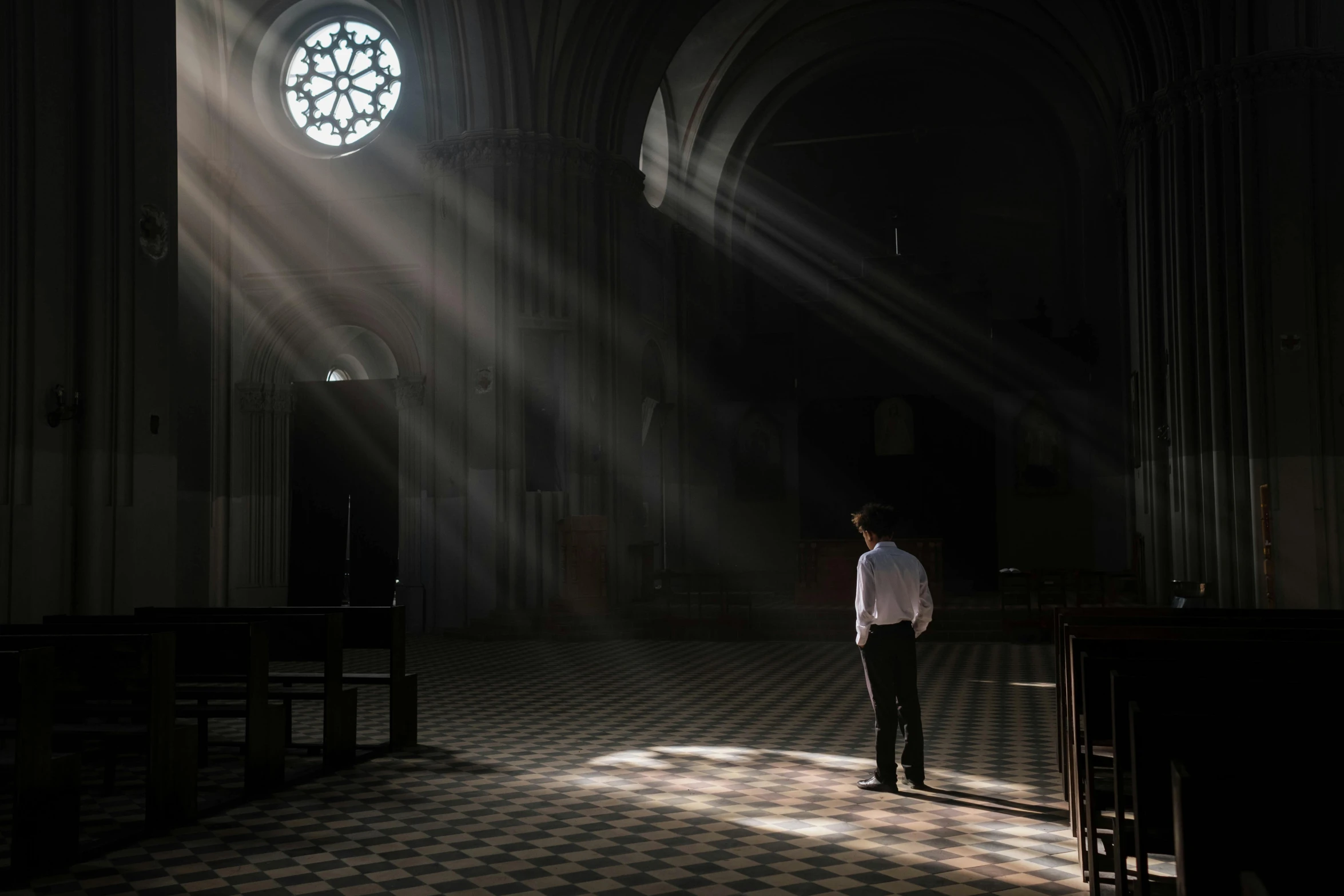 a man in a white shirt standing in a church, a picture, unsplash contest winner, light and space, light casting onto the ground, mournful, cerpuscular rays, photograph taken in 2 0 2 0