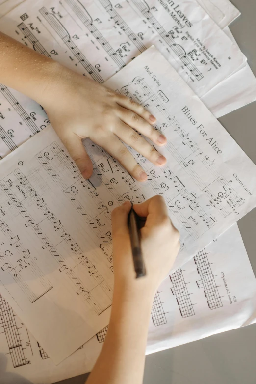 a person sitting at a table with papers and a pen, a child's drawing, by Robert Medley, pexels, plays music, equations, background image, a high angle shot