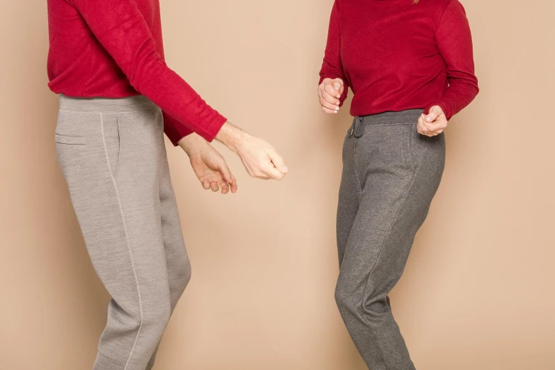 a couple of women standing next to each other, by Nina Hamnett, red sweater and gray pants, hands straight down, taupe, sport clothing