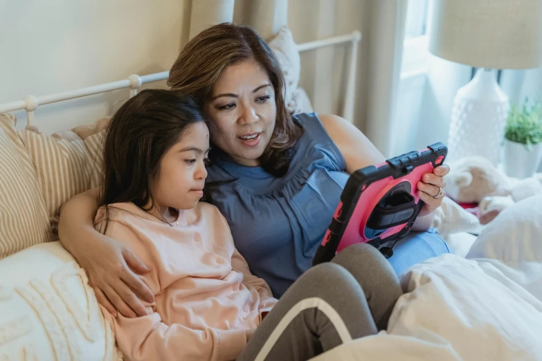 a woman sitting next to a little girl on a bed, a cartoon, pexels contest winner, using a magical tablet, looking across the shoulder, joy ang, netflix