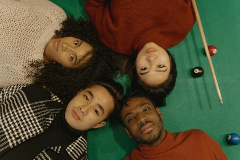 a group of people laying on top of a pool table, trending on pexels, realism, diverse faces, promo still, 1 / 4 portrait, coloured