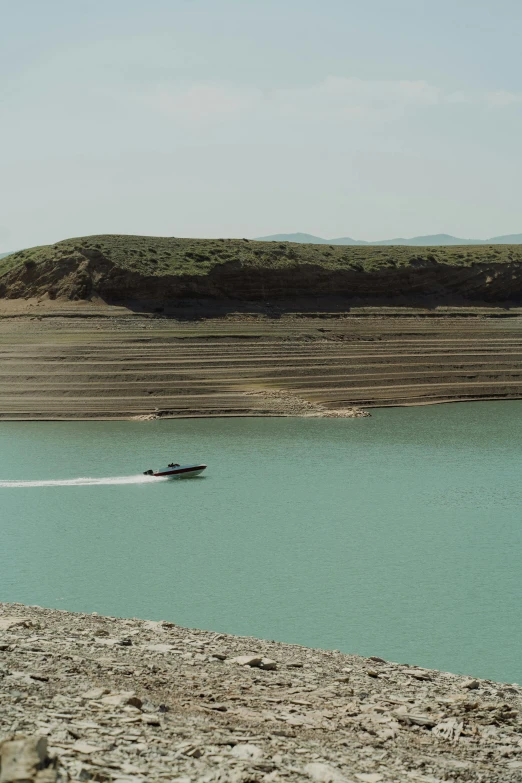 a boat in the middle of a large body of water, by Muggur, in dusty open pit mine, al - qadim, low quality photo, loosely cropped