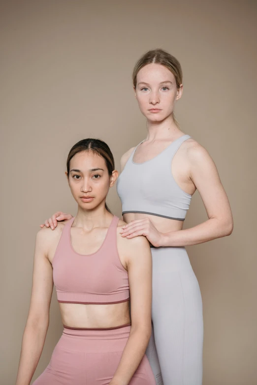 two women in sports wear posing for a picture, a colorized photo, inspired by Vanessa Beecroft, unsplash, renaissance, pink and grey muted colors, photoshoot for skincare brand, croptop, no - text no - logo