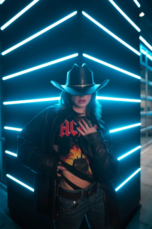 a woman standing in front of a wall with neon lights, an album cover, trending on pexels, holography, wearing a cowboy hat, gothic clothing, wwe, leather clothing