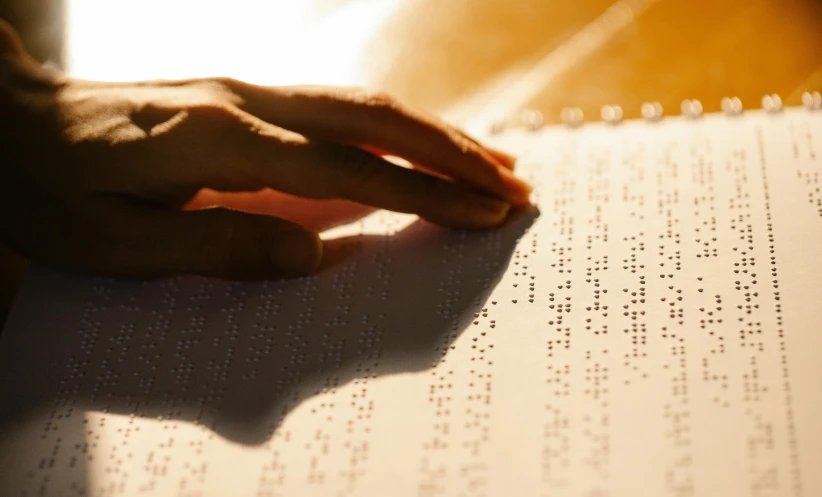 a close up of a person's hand on a book, a stipple, unsplash, ascii art, warm sunlight shining in, blind, varying dots, marfan syndrome