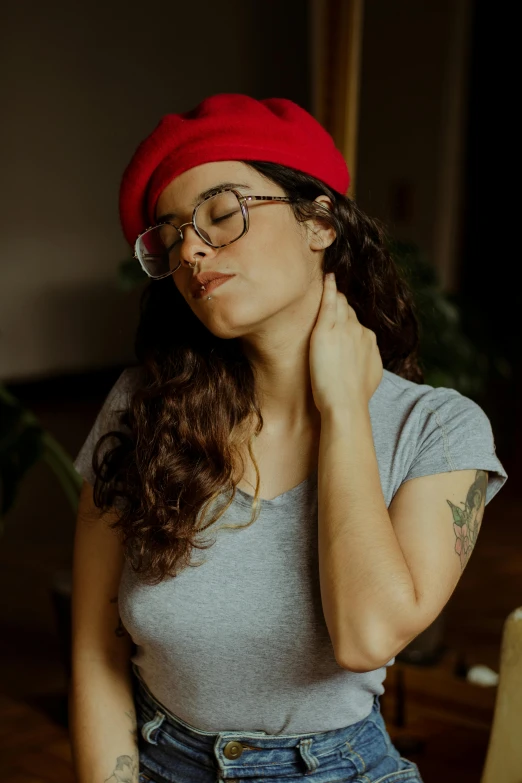 a woman wearing glasses and a red hat, an album cover, inspired by Elsa Bleda, trending on pexels, renaissance, swollen muscles, gentle calm doting pose, indoor picture, focused on neck