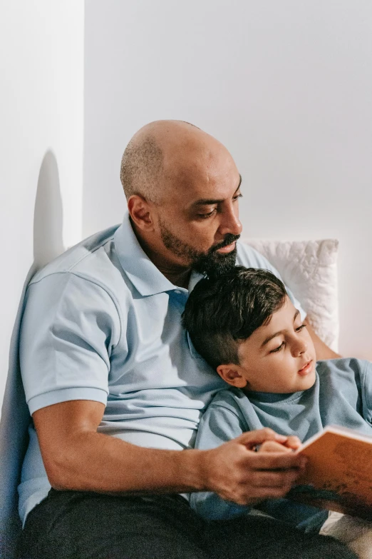 a man reading a book to a young boy, pexels contest winner, romanticism, movie still of a tired, profile image, hispanic, bedhead