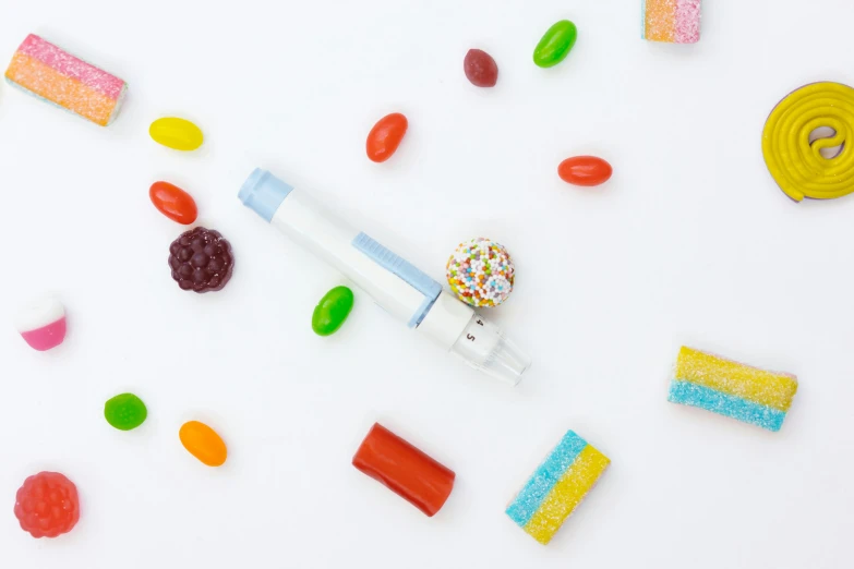 a white table topped with lots of different types of candies, inspired by Damien Hirst, trending on pexels, figuration libre, holding a small vape, set against a white background, pod racer, colored marker