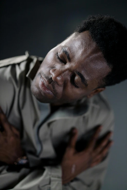 a man with his hands on his chest, an album cover, by Paul Davis, pexels, godwin akpan, solo male weary soldier, video still, comforting