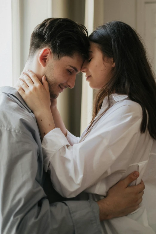 a man and a woman embracing in front of a window, trending on pexels, wearing a light shirt, tender, ad image, female