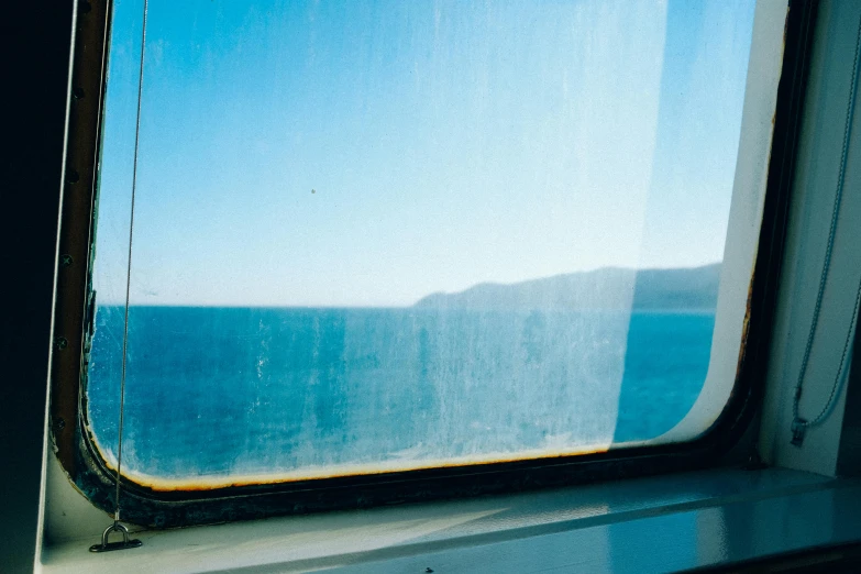 a window with a view of the ocean, a polaroid photo, by Nathalie Rattner, unsplash, romanticism, train far, half blue, 1999 photograph, portholes