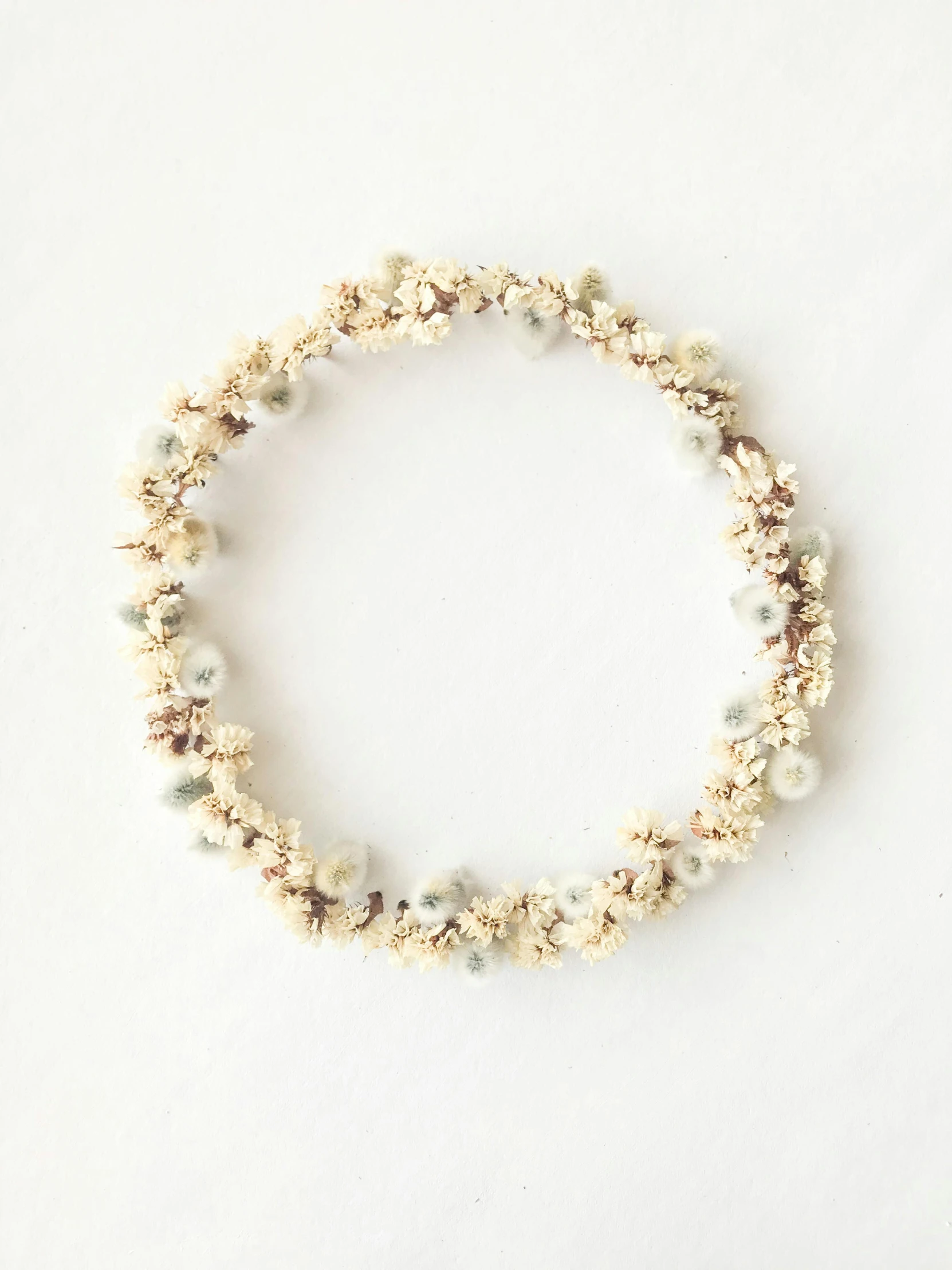 a beaded bracelet on a white surface, by Ellen Gallagher, hurufiyya, with a halo of unkempt hair, white flower crown, ignant, bali