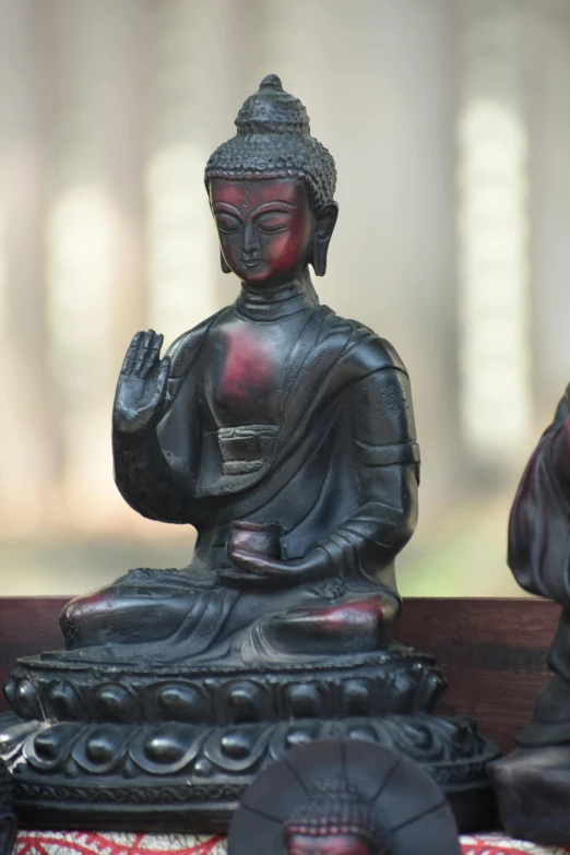 a couple of statues sitting on top of a wooden bench, dharma artifacts, multicoloured, religious, brown