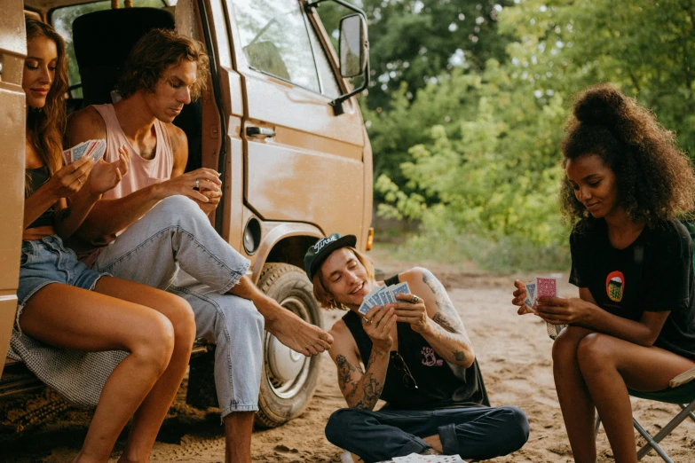 a group of people sitting around a camper van, pexels contest winner, playing cards, aboriginal australian hipster, lecherous pose, wearing dirty travelling clothes