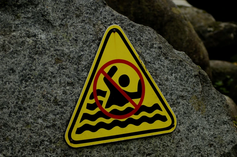 a warning sign sitting on top of a rock, a picture, pexels, graffiti, people swimming, avatar image, no - text no - logo, maintenance