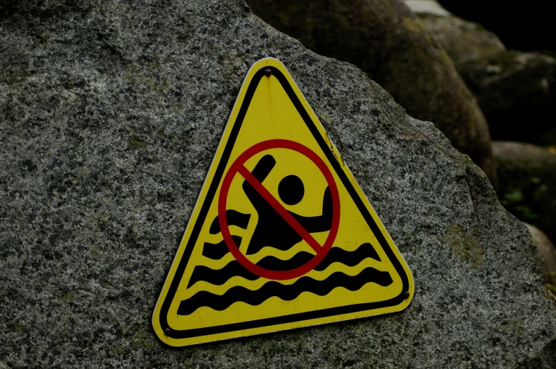 a warning sign sitting on top of a rock, a picture, pexels, graffiti, people swimming, avatar image, no - text no - logo, maintenance