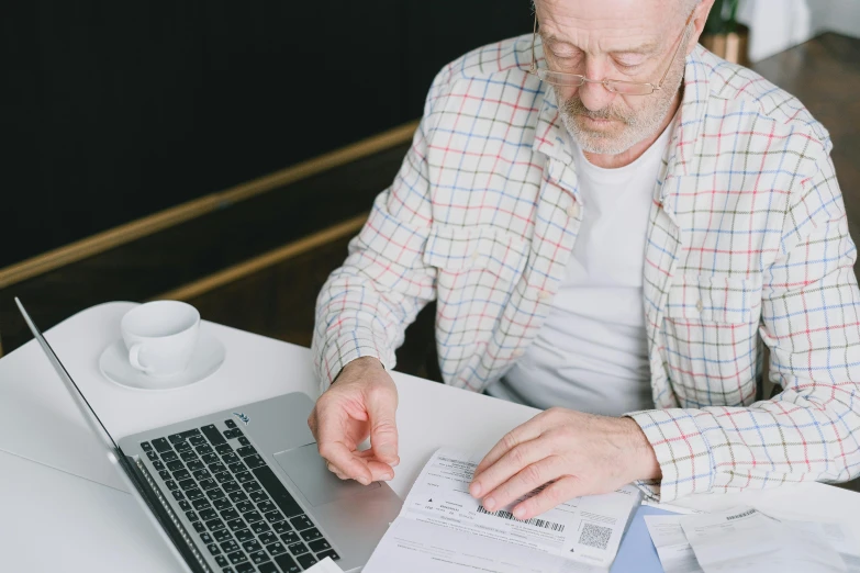 a man sitting at a table with a laptop and papers, pexels contest winner, old gigachad with grey beard, pixelated, man standing, healthcare