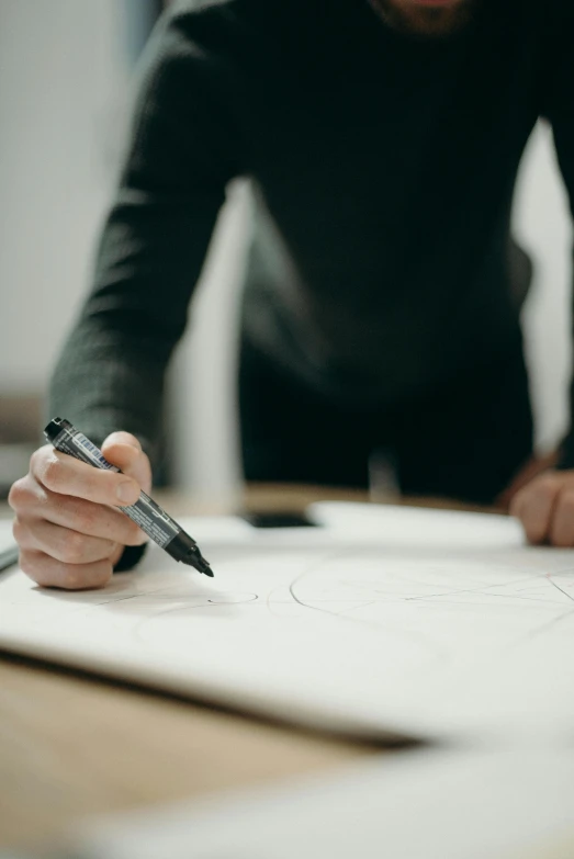 a man writing on a piece of paper with a pen, a drawing, by Oskar Lüthy, pexels contest winner, arbeitsrat für kunst, round design, on canvas, professional model, engineering