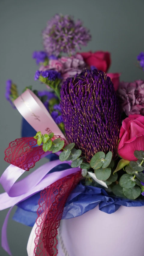 a close up of a vase with flowers in it, purple ribbons, vibrant dark mood, wrapped in flowers, zoomed in