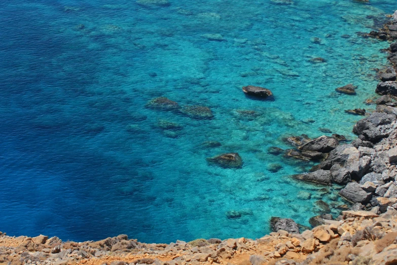 a large body of water next to a rocky shore, pexels contest winner, hurufiyya, warm shades of blue, glass antikythera, thumbnail, coral sea bottom