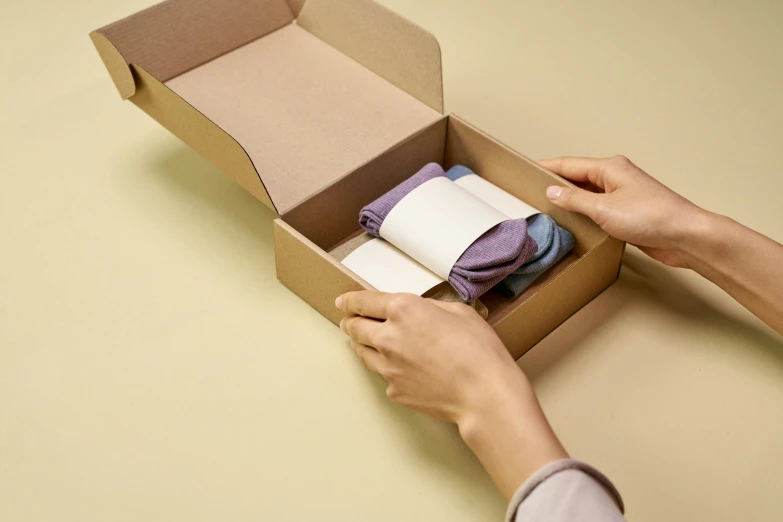 a person holding a pair of socks in a box, private press, multicoloured, opening shot, assemble, product shot