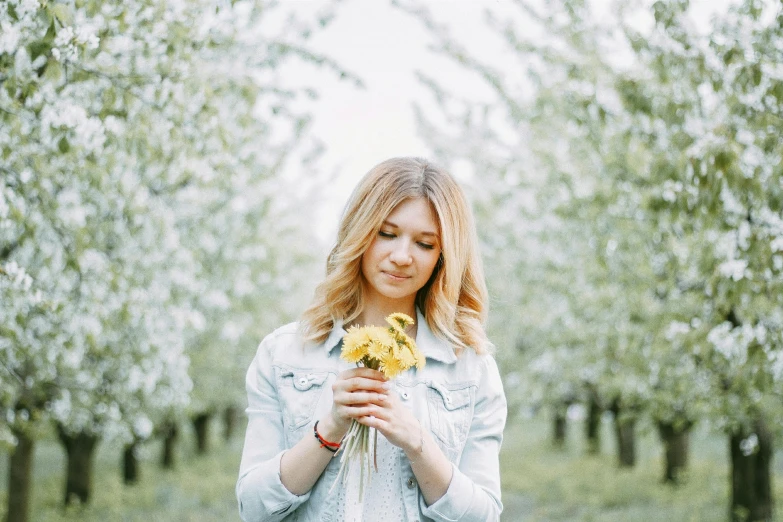 a woman holding a bunch of yellow flowers, pexels contest winner, apple blossoms, sydney sweeney, looking cute, 15081959 21121991 01012000 4k