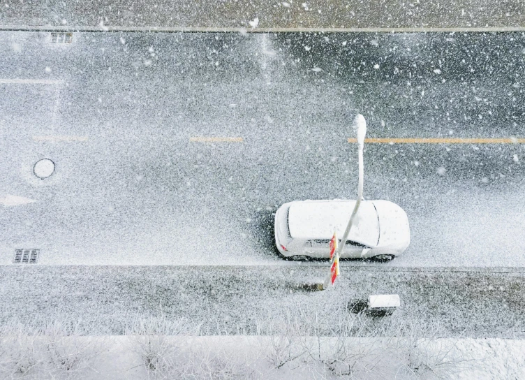 a car is parked on the side of the road in the snow, a photorealistic painting, inspired by Robert Bechtle, pexels contest winner, conceptual art, aerial view top down, jingna zhang, low pressure system, light snowfall