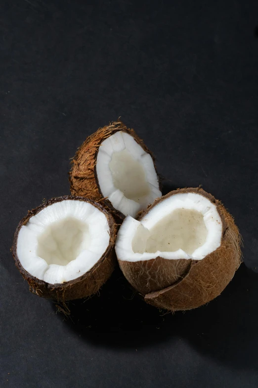 a couple of coconuts sitting on top of a table, in front of a black background, detailed product image, panel, local foods