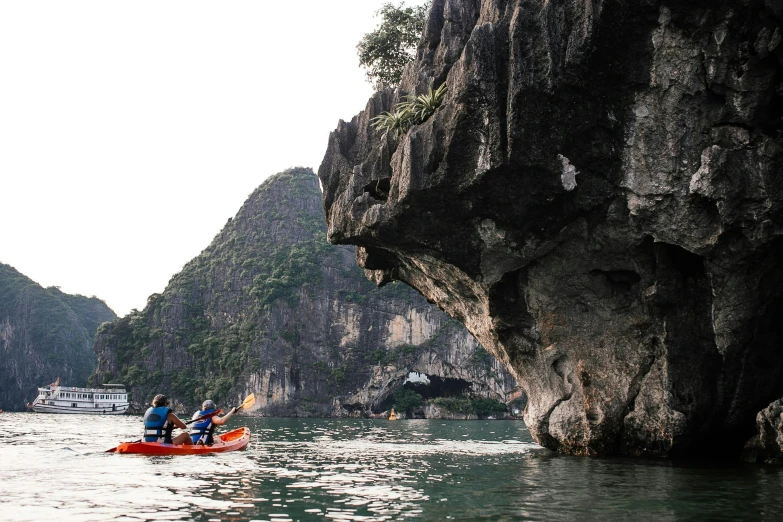 a couple of people on a kayak in a body of water, a picture, overgrown stone cave, quy ho, epic land formations, conde nast traveler photo