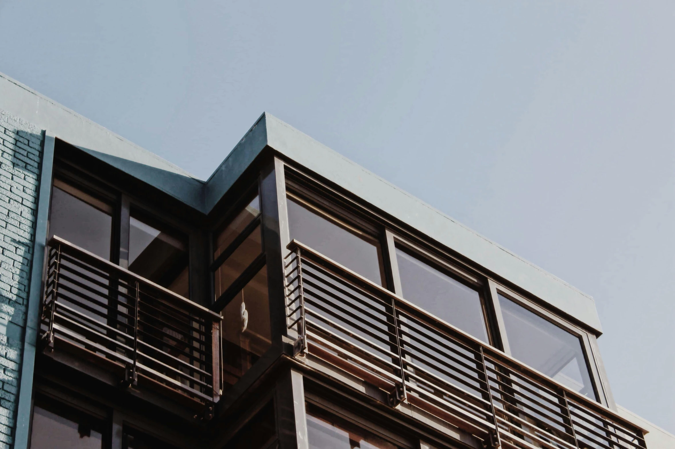 a tall building with lots of windows and balconies, a screenshot, unsplash, modernism, wooden house, brown, low-angle, rooftop