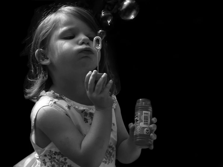 a black and white photo of a little girl blowing bubbles, a black and white photo, black background hyperrealism, good times photograph, sweet, toddler