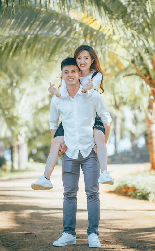 a man carrying a woman on his back, a picture, by Robbie Trevino, pexels, with palm trees in the back, asian female, frontal pose, 15081959 21121991 01012000 4k