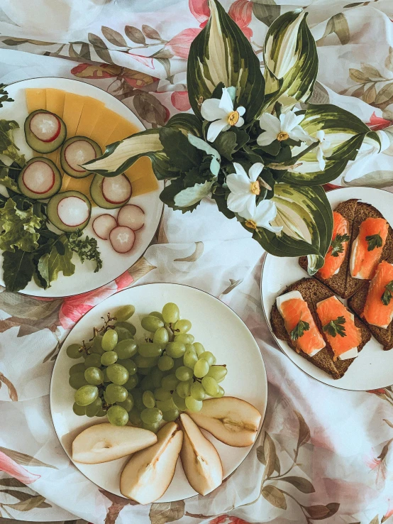 a table topped with plates of food next to a vase of flowers, unsplash, brown bread with sliced salo, fruit eyes, low quality photo, greens)