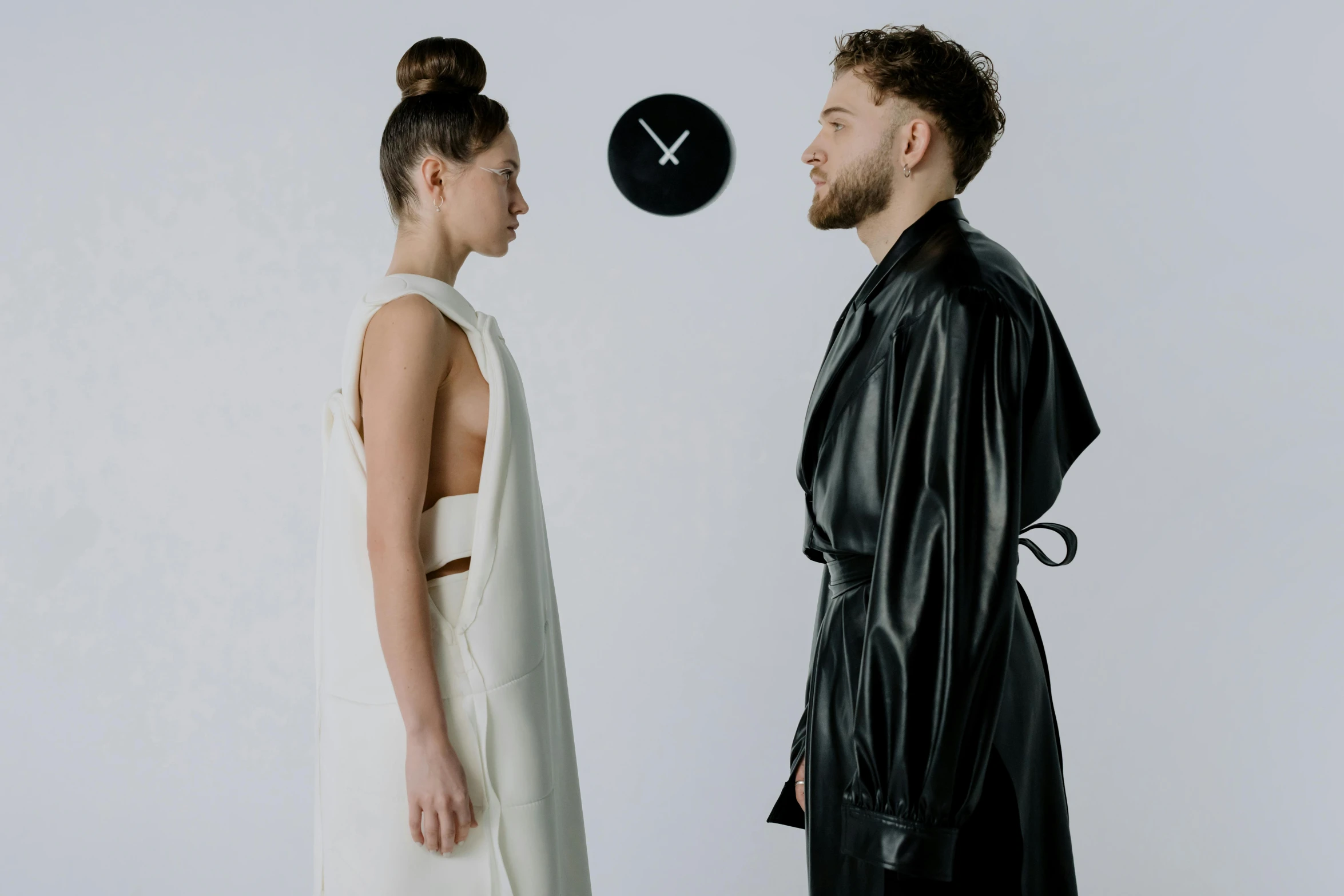 a man and a woman standing next to each other, inspired by Marina Abramović, trending on pexels, bauhaus, clock, leather robes, at a fashion shoot, bride and groom