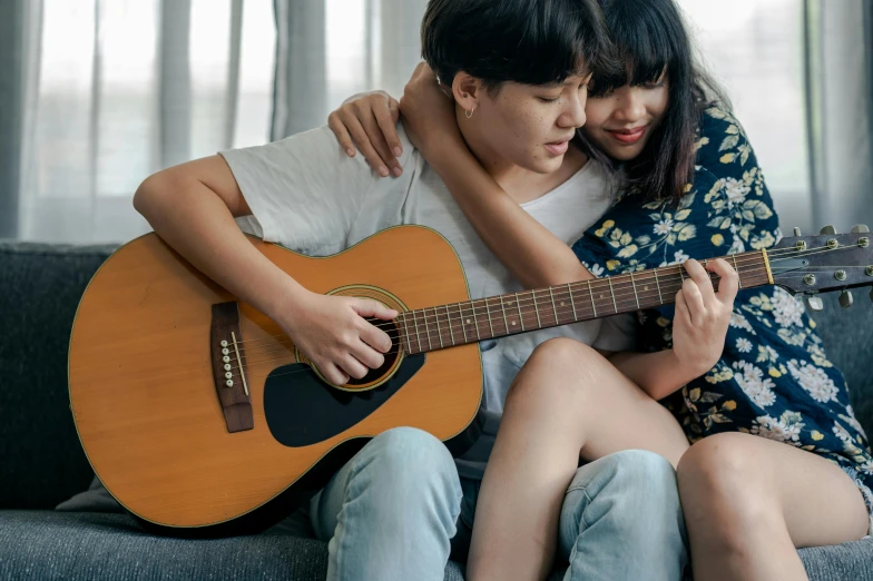 a man and a woman sitting on a couch with a guitar, trending on pexels, realism, asian women, hugging her knees, thumbnail, guide