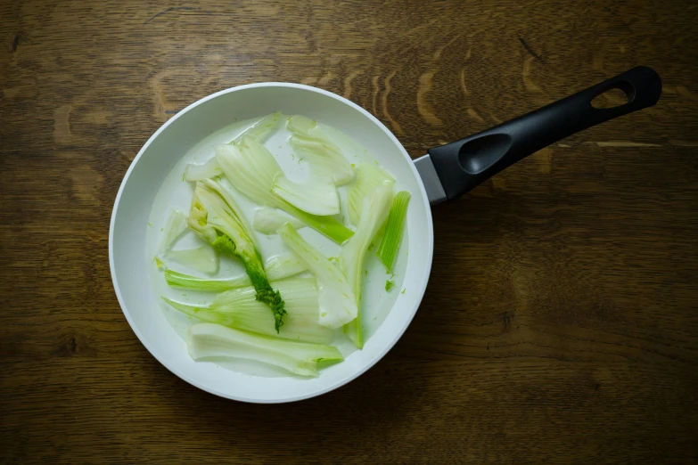 a pan filled with chopped celery on top of a wooden table, inspired by Géza Dósa, unsplash, renaissance, ethereal white dripping tar, white sweeping arches, pale milky white porcelain skin, dwell