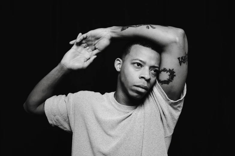 a black and white photo of a man with a tattoo on his arm, by Maurycy Gottlieb, kehinde wiley, gustavo fring, with a cool pose, halfbody headshot