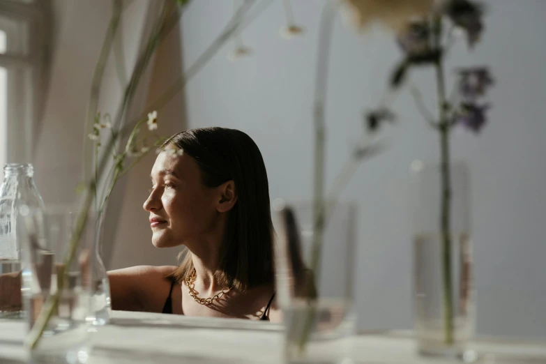 a woman sitting at a table looking out a window, a character portrait, by Emma Andijewska, pexels contest winner, light and space, flowers on heir cheeks, photoshoot for skincare brand, at a dinner table, portrait sophie mudd
