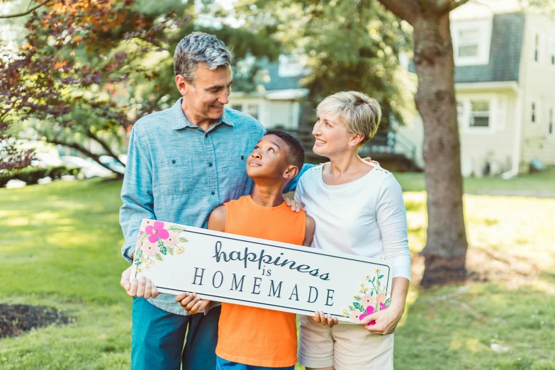 a family holding a sign that says happiness is homemade, pexels, naive art, romantic lead, cottage core, grandma, handsome