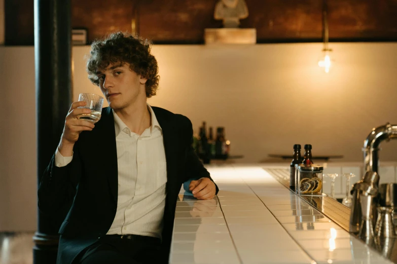 a man sitting at a bar with a glass in his hand, an album cover, pexels contest winner, timothee chalamet, whisky, profile image, classy