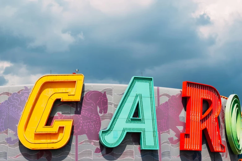 a close up of a sign with a cloudy sky in the background, by Carey Morris, pexels contest winner, pop art, a busy arcade, letter a, cars, dreamland