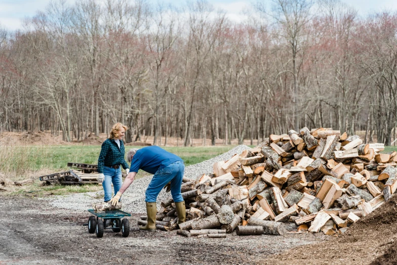 a couple of people standing next to a pile of wood, jenna barton, filling the frame, outdoor photo, thumbnail