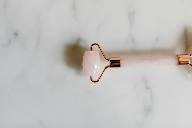 a pink toothbrush sitting on top of a marble counter, by Emma Andijewska, trending on pexels, copper spiral hair decorations, gemstone forehead, spoon placed, the stone is rolling up