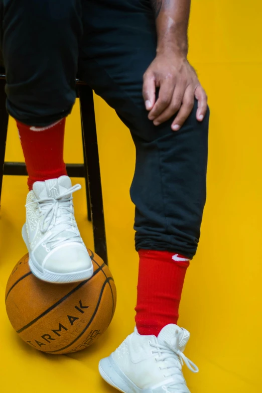 a man sitting on top of a basketball ball, socks, vibrant red, curated collections, trending photo