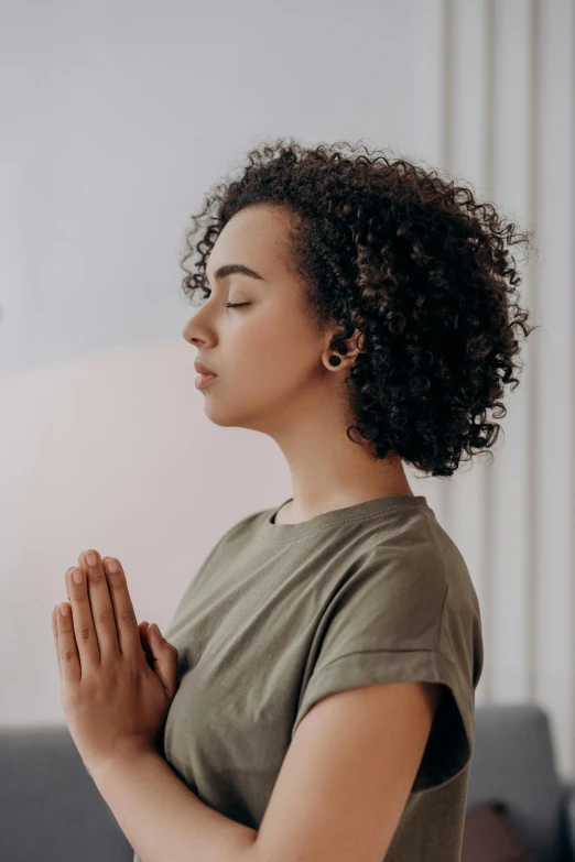 a woman is praying in a living room, trending on pexels, renaissance, indian girl with brown skin, sukhasana, on grey background, curls