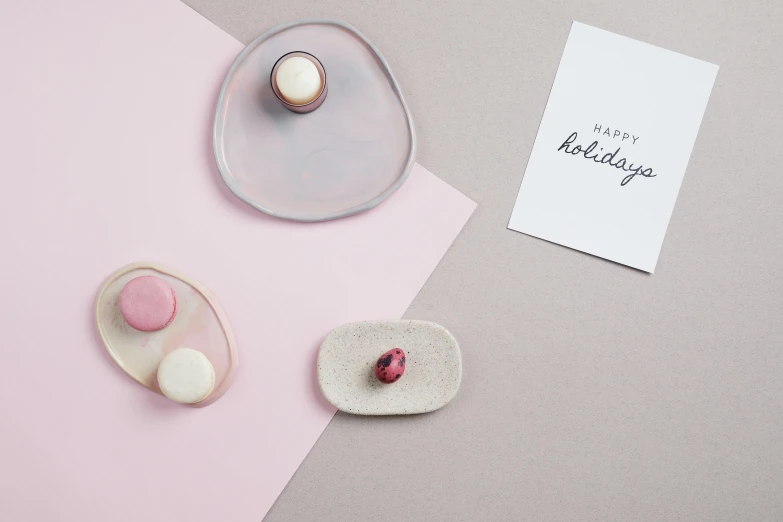 a cupcake sitting on top of a plate next to a card, inspired by Okada Hanko, featured on pinterest, minimalism, floating stones, silicone skin, holiday, white and pink