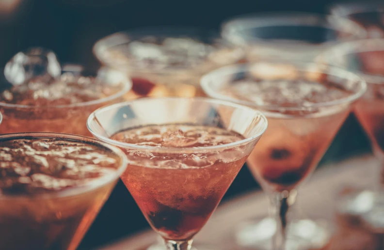 a group of wine glasses sitting on top of a wooden table, an album cover, pexels, drinking a martini, background image, manuka, cocktail bar