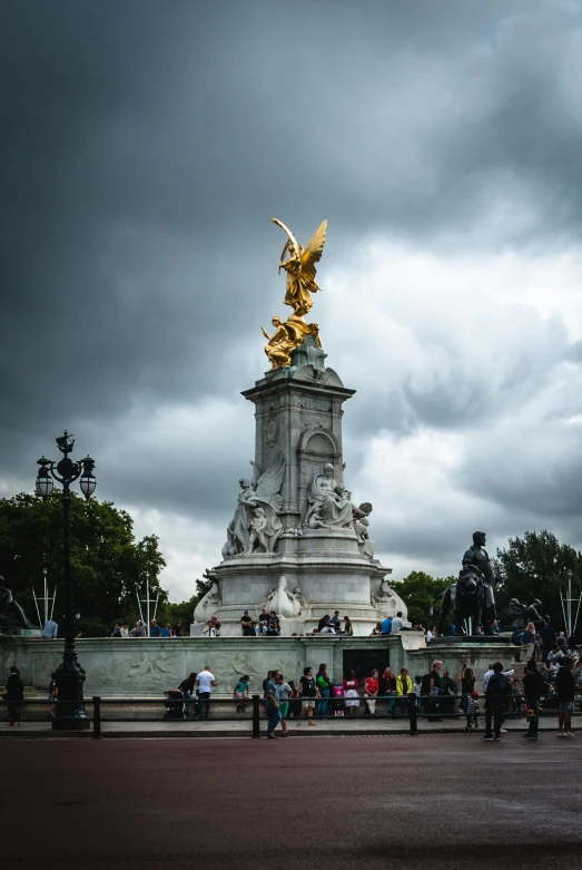 a group of people that are standing in front of a statue, large crown, stormy weather, during the day, london architecture