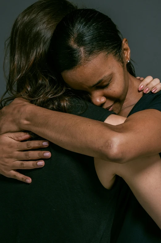 a couple of people that are hugging each other, promo image, womanhood”, recovering from pain, dark backdrop