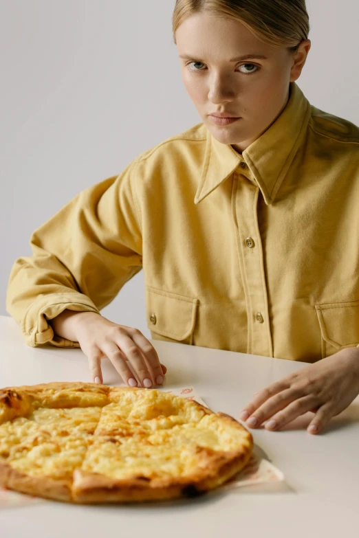 a woman sitting at a table with a pizza in front of her, inspired by Sarah Lucas, trending on unsplash, hyperrealism, yellow clothes, cropped shirt with jacket, teenage boy, ignant